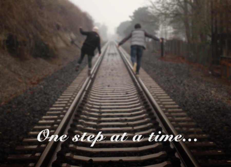 Two people walking a railway line into the fog, captioned "One step at a time..."